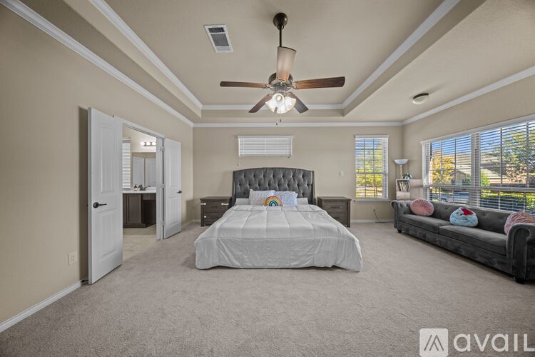 A bedroom with a large bed and a ceiling fan.