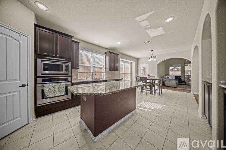 A kitchen with a marble island and a dining area.
