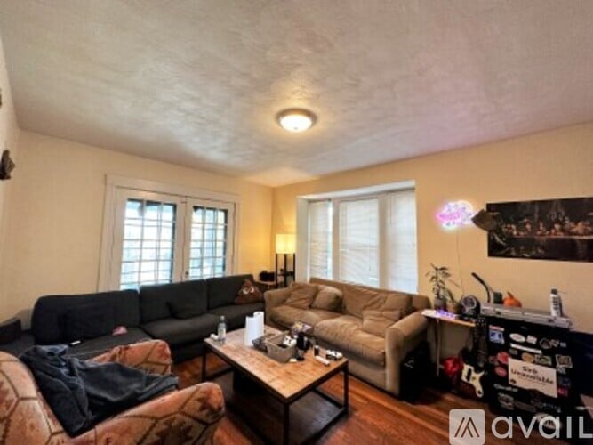 A living room with a black couch, a brown couch, and a coffee table.