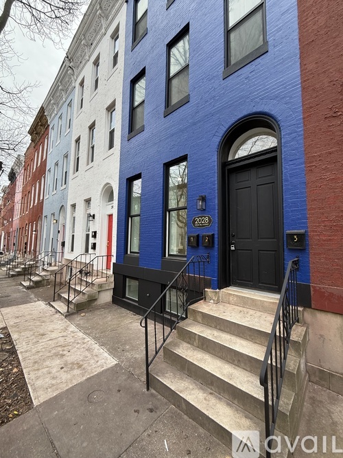 A blue and red building with a black door and number 2028 on it.