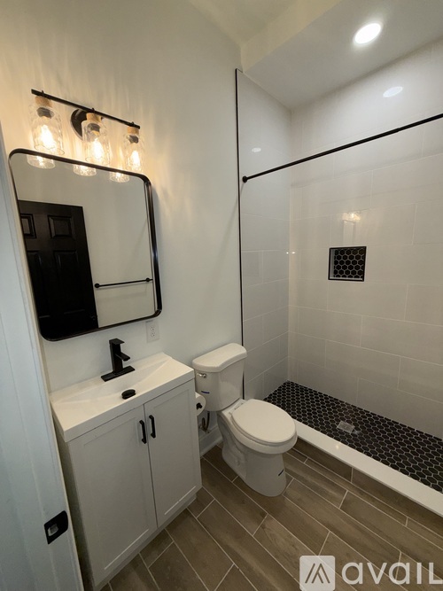 A bathroom with a toilet, sink, and mirror.