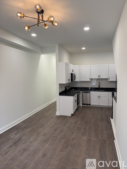 A kitchen with white cabinets and a wooden floor.