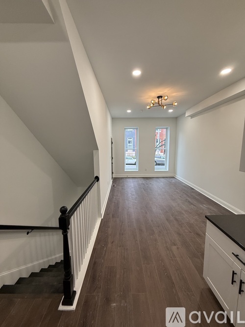 A long hallway with wood floors and a chandelier.