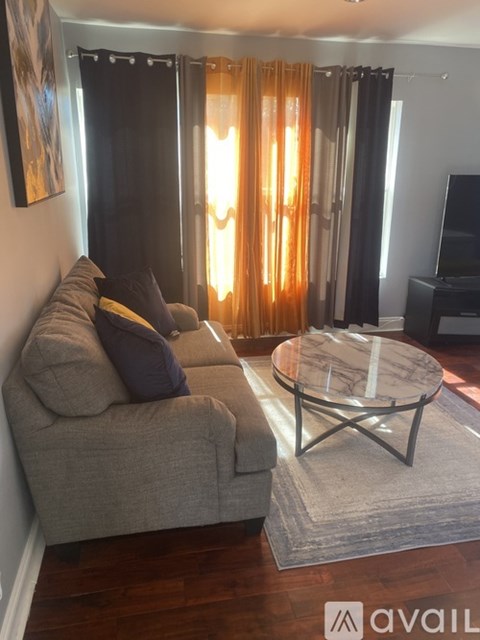A living room with a grey couch and a glass coffee table.