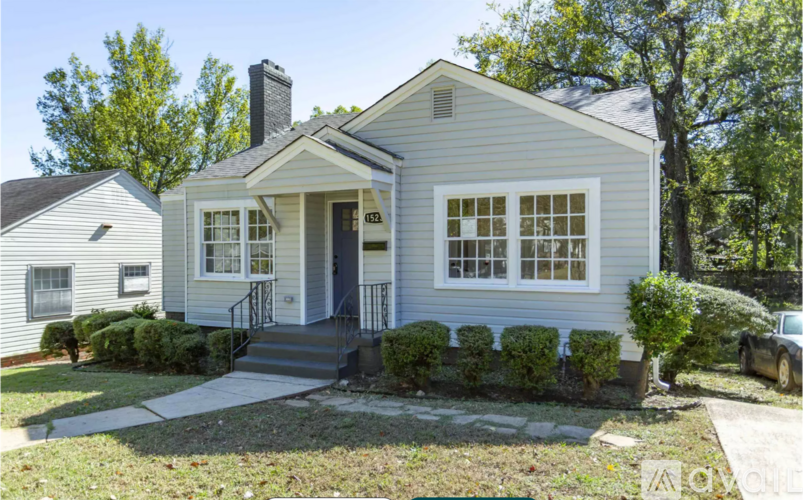 A small house with a front porch and a car parked in the driveway.