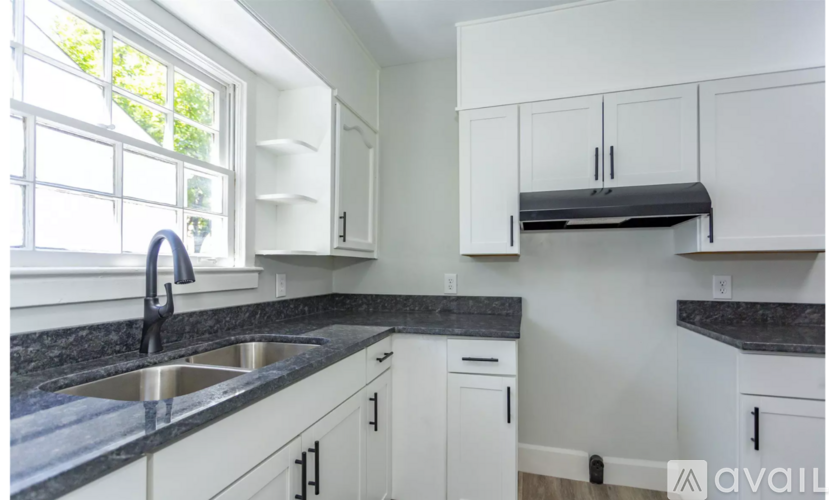A kitchen with white cabinets and a black countertop.