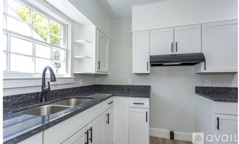 A kitchen with white cabinets and a black countertop.