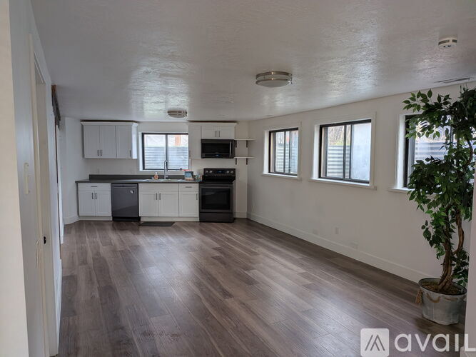 A spacious kitchen with wooden floors and white walls.