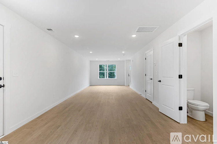 A spacious room with wooden flooring and white walls.