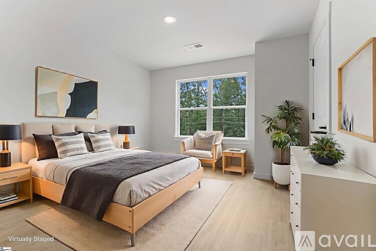 A bedroom with a large bed, a chair, and a potted plant.