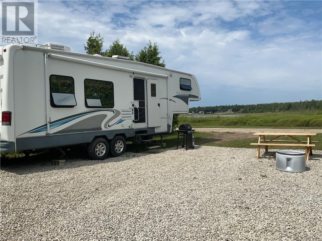 A white RV is parked on a gravel lot.