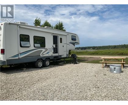 A white RV is parked on a gravel lot.
