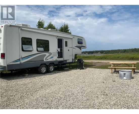 A white RV is parked on a gravel lot.