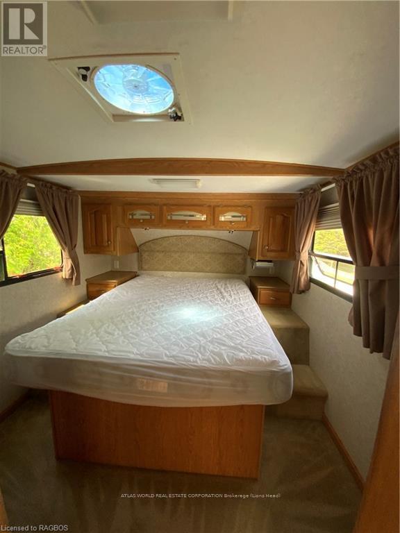 A bedroom with a bed, wooden cabinets, and a skylight.