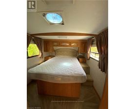A bedroom with a bed, wooden cabinets, and a skylight.
