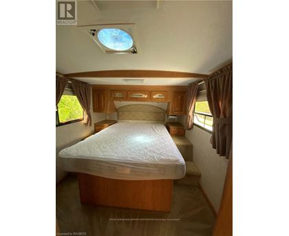 A bedroom with a bed, wooden cabinets, and a skylight.