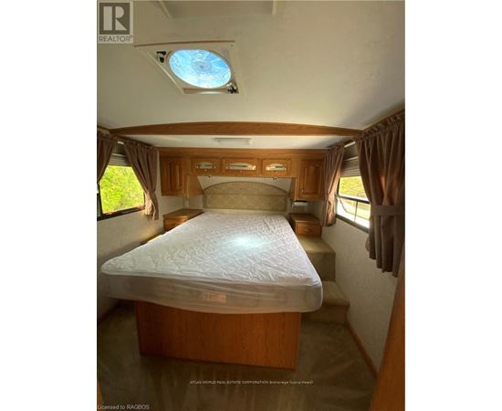 A bedroom with a bed, wooden cabinets, and a skylight.