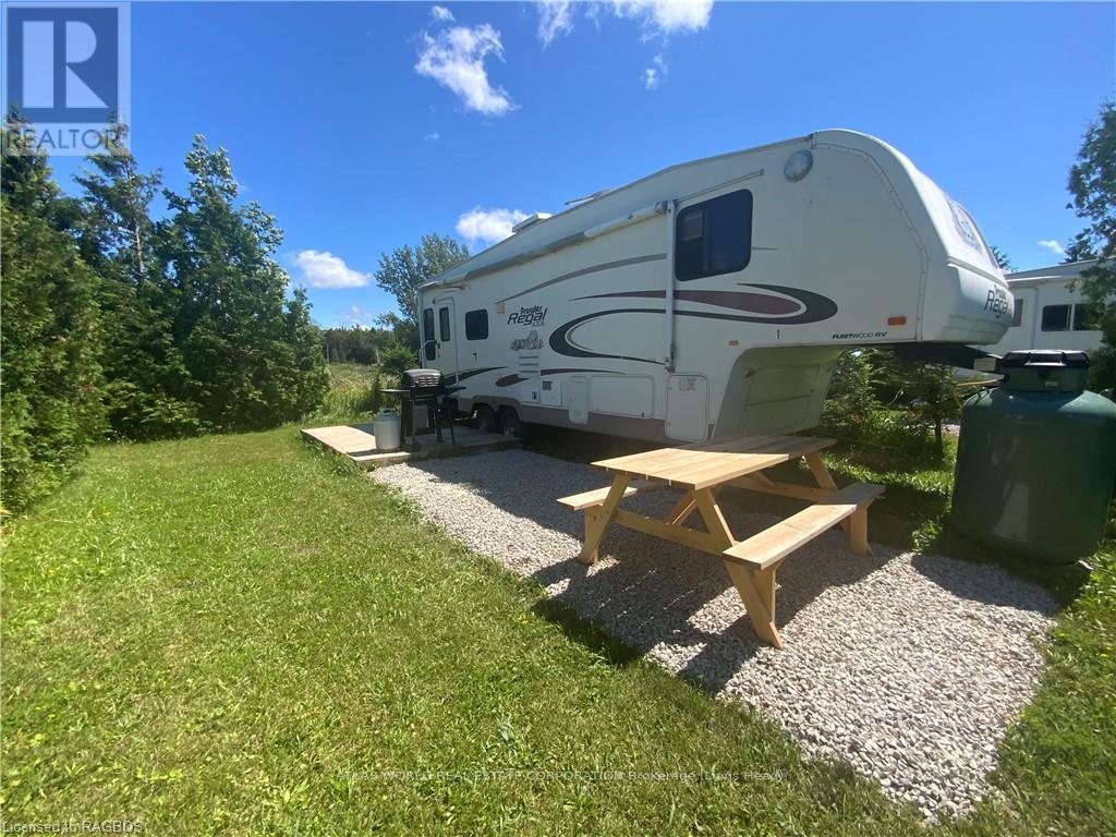 A white RV is parked in a grassy area with a picnic table in front of it.