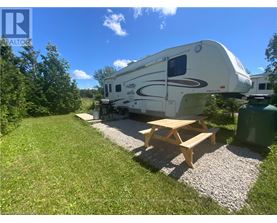 A white RV is parked in a grassy area with a picnic table in front of it.