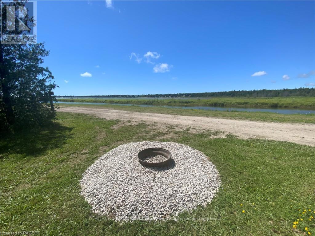 A tire surrounded by gravel sits in the middle of a grassy area.