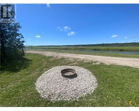 A tire surrounded by gravel sits in the middle of a grassy area.