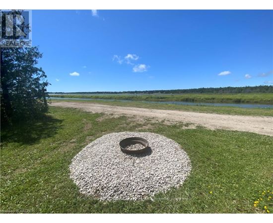 A tire surrounded by gravel sits in the middle of a grassy area.