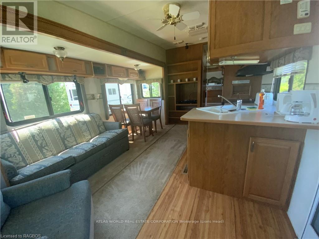 A well-lit kitchen and living room area with wooden flooring and furniture.