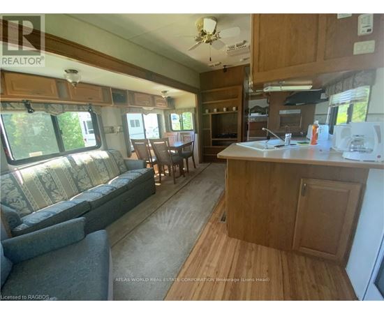 A well-lit kitchen and living room area with wooden flooring and furniture.