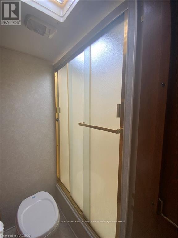 A white toilet in a small bathroom with a glass shower door.