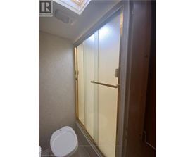 A white toilet in a small bathroom with a glass shower door.