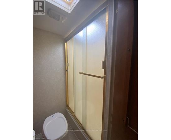 A white toilet in a small bathroom with a glass shower door.