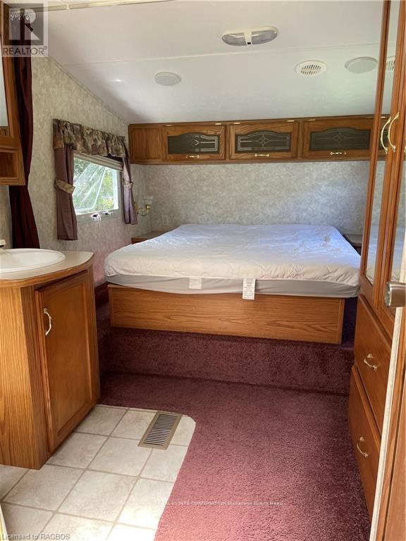 A bedroom with a bed, sink, and wooden cabinets.
