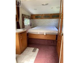 A bedroom with a bed, sink, and wooden cabinets.