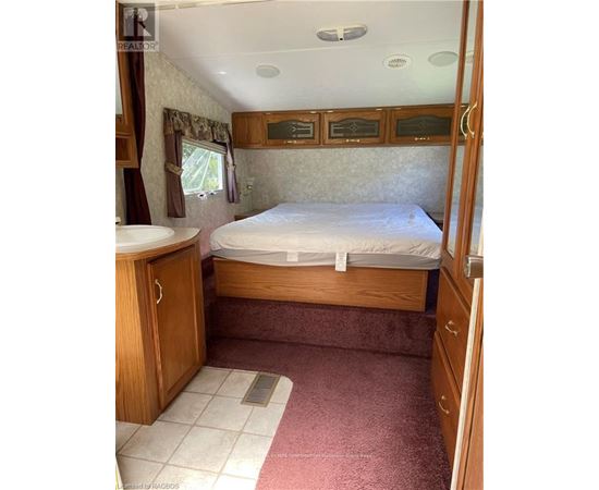 A bedroom with a bed, sink, and wooden cabinets.