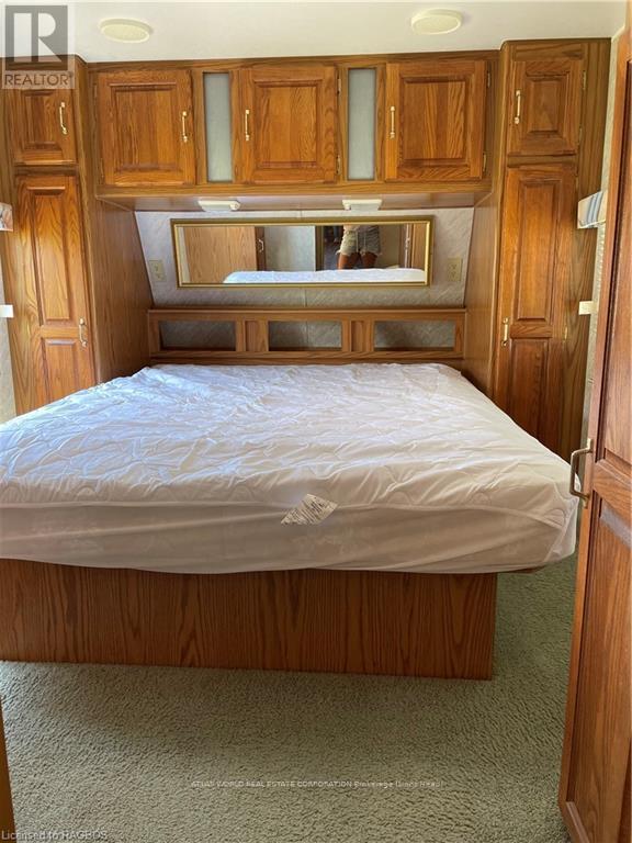 A bedroom with a bed, wooden cabinets, and a mirror above the bed.