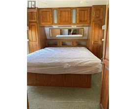 A bedroom with a bed, wooden cabinets, and a mirror above the bed.