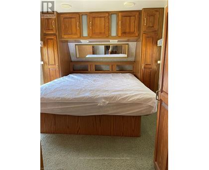 A bedroom with a bed, wooden cabinets, and a mirror above the bed.
