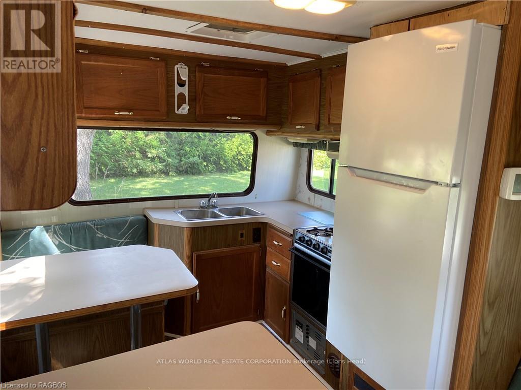 A kitchen area with a white fridge, sink, and stove.