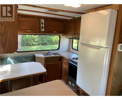 A kitchen area with a white fridge, sink, and stove.