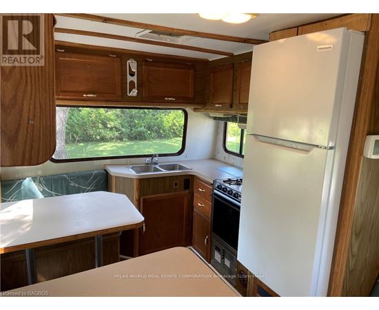 A kitchen area with a white fridge, sink, and stove.