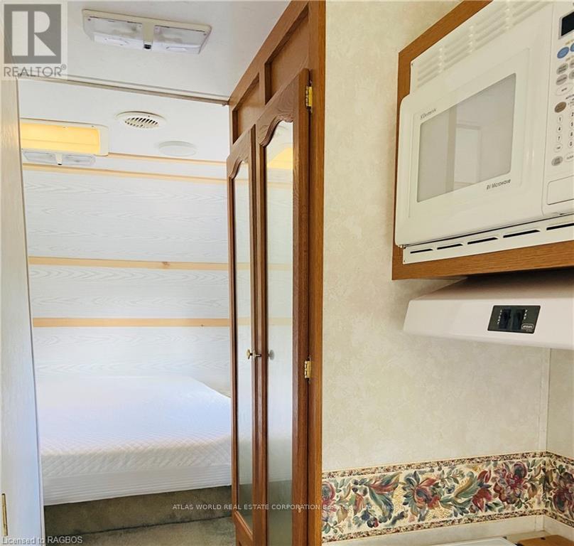 A small bedroom with a bed, a microwave, and a wooden door.