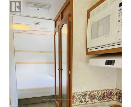 A small bedroom with a bed, a microwave, and a wooden door.