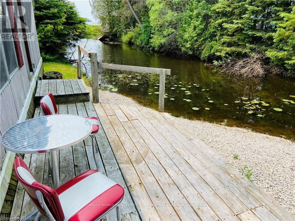 A wooden deck with a table and chairs overlooking a river.