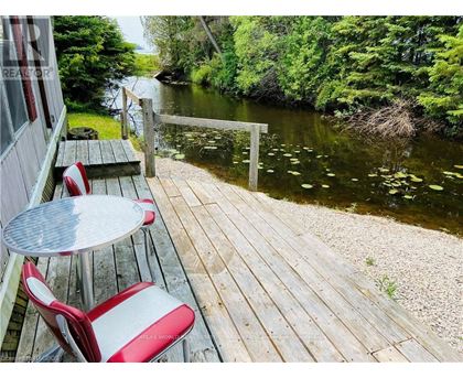 A wooden deck with a table and chairs overlooking a river.