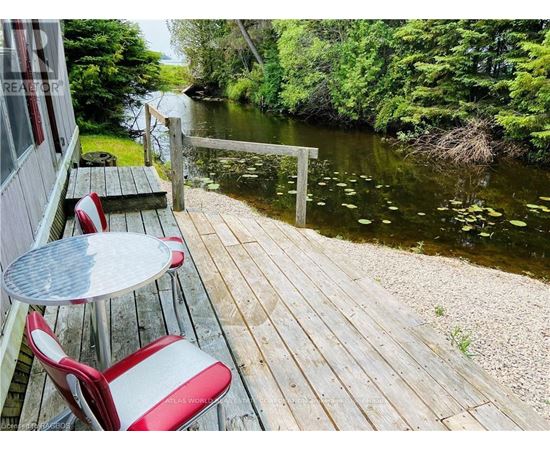 A wooden deck with a table and chairs overlooking a river.