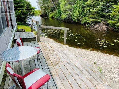 A wooden deck with a table and chairs overlooking a river.