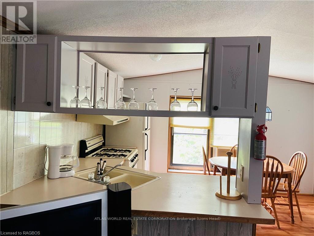 A kitchen with a white counter top and wooden chairs.