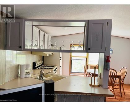 A kitchen with a white counter top and wooden chairs.