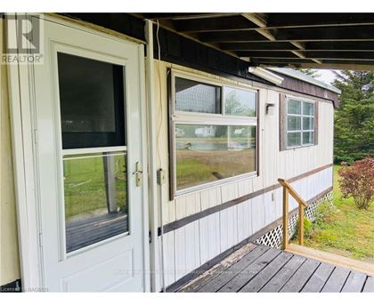 A white door and window on a house with a wooden deck.
