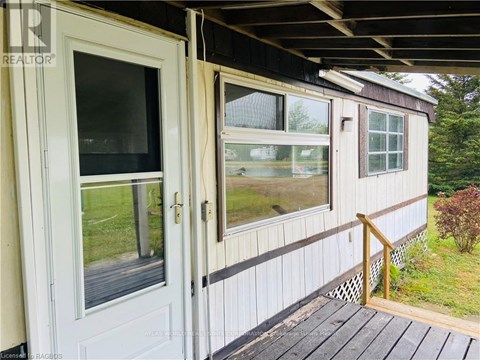 A white door and window on a house with a wooden deck.